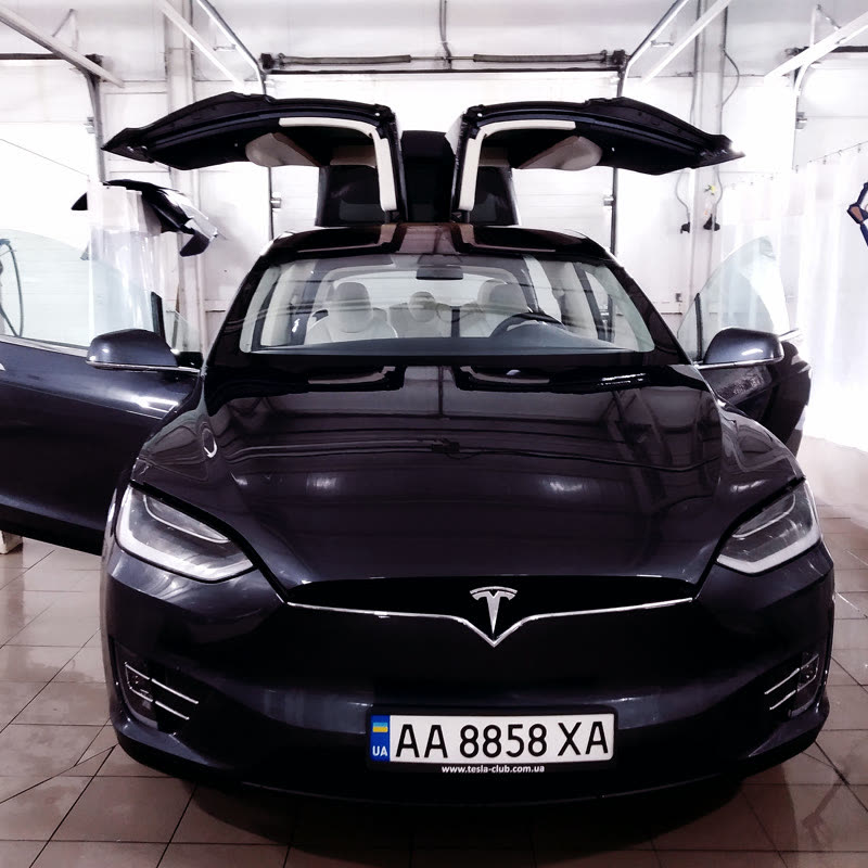 Tesla Model X із піднятими дверима в боксі мийки